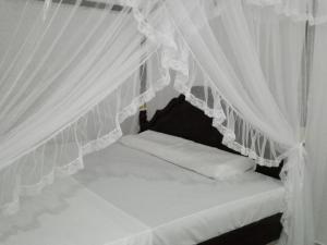 a bed with white drapes in a room at Mirissa Cocoon in Mirissa