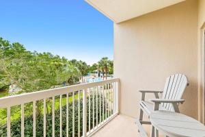 a balcony with two white chairs and a table at TOPS'L Summit 207A in Destin +7 photos