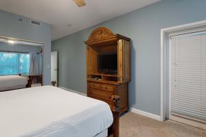 a bedroom with a bed and a dresser with a television at TOPS'L Summit 210 in Destin