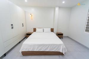a white bedroom with a large white bed in it at Phu Hai Apartment in Dong Hoi