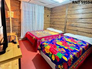 a bedroom with a bed with a colorful blanket at Cabañas rurales Aldea de Cabal - Naturaleza y Sabor cerca a Termales Reservamos tu entrada a termales Santa Rosa in Santa Rosa de Cabal