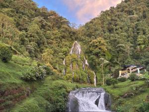 a waterfall in the middle of a lush green mountain at Cabañas rurales Aldea de Cabal - Naturaleza y Sabor cerca a Termales Reservamos tu entrada a termales Santa Rosa in Santa Rosa de Cabal