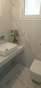 a white bathroom with a sink and a toilet at Alora Cosy Suite in Kefalos