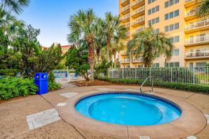a swimming pool with palm trees and a building at TOPS'L Summit VI in Destin
