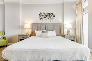 a white bedroom with a large bed and two lamps at TOPS'L Summit 1108A in Destin
