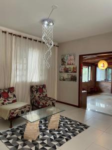 a living room with a glass table and a chandelier at Refúgio Alto do Pinhal in Santo Antônio do Pinhal +6 photos