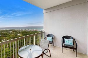 a balcony with two chairs and a glass table at Top-Floor Studio with Ocean Views and Pool in Destin