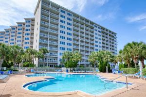 a large apartment building with a swimming pool and palm trees at TOPS'L Summit 107b in Destin