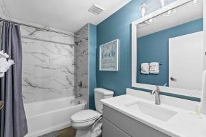 a bathroom with a white toilet and a tub and a sink at TOPS'L Summit 809 2 Bedroom in Destin