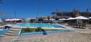 a swimming pool in a resort with tables and umbrellas at Coral Loft in Antón Lizardo