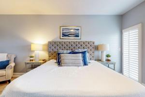 a bedroom with a large white bed with blue pillows at 4th-Floor Condo with Shared Pool and WiFi in Destin