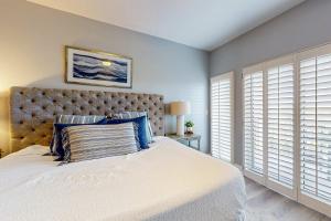 a bedroom with a large white bed with blue pillows at 4th-Floor Condo with Shared Pool and WiFi in Destin +33 photos