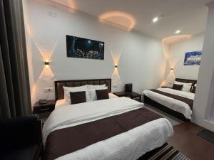 a bedroom with two beds and lights on the wall at FarahBakshResidency in Jāmb