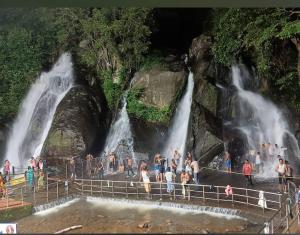 a group of people standing in front of waterfall at Five Falls RAMANA VILLA in Kuttālam