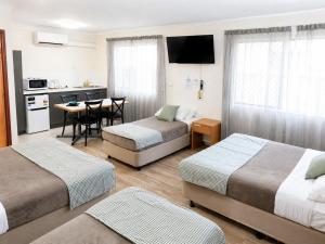 a hotel room with three beds and a table and a kitchen at Cedar Lodge Motel in Townsville