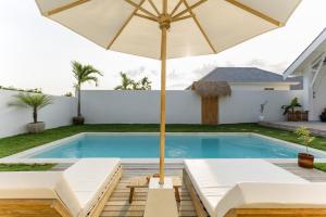 an umbrella sitting next to a swimming pool at Uluwatu - Beach Villa 5 in Uluwatu