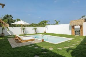 a backyard with a swimming pool and an umbrella at Uluwatu - Beach Villa 5 in Uluwatu