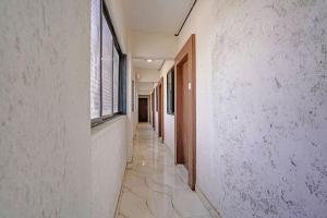 an empty corridor of a building with white walls and windows at FabHotel Red Rose Palghar in Nale Sopāra