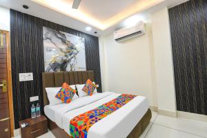 a bedroom with a large bed with colorful pillows at FabHotel Samarth Residency By the Arrow in New Delhi