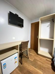 a room with a desk with a television and a chair at Queiroz Palace Hotel in Siqueira Campos