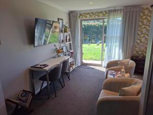a living room with a desk and a table with chairs at Ra-ata Farm in Rangiora