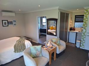 a bedroom with a bed and two chairs and a table at Ra-ata Farm in Rangiora