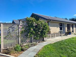 a house with a fence with a flowering bush at Ra-ata Farm in Rangiora