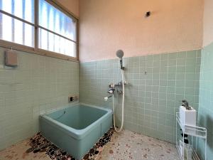 a bathroom with a blue tub and a window at Casa di acero in Kikuchi