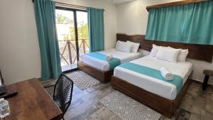 a bedroom with two beds and a table and a window at Hotel y Beach Club Casa Mia Xulha -Bacalar in Xul-Ha +41 photos