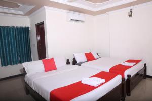 two beds in a room with red and white sheets at Sai Kirshanth Residency in Karaikal