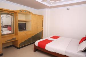 a bedroom with a bed and a cabinet and a television at Sai Kirshanth Residency in Karaikal