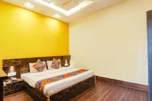 a bedroom with a bed with a yellow wall at FabHotel Ambika Dx in Gwalior +16 photos