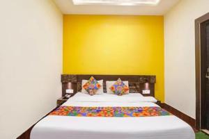 a bedroom with a large bed with a yellow wall at FabHotel Ambika Dx in Gwalior