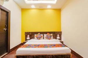 a bedroom with a large bed with a yellow wall at FabHotel Ambika Dx in Gwalior
