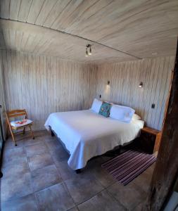 a bedroom with a bed and a chair in it at Cabañas Urmeneta Sur in Tongoy