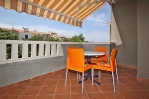 a patio with a table and chairs on a balcony at Apartmani Ruža in Novalja