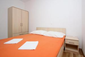 a bedroom with a large orange bed with a cabinet at Apartmani Ruža in Novalja