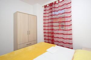 a bedroom with a bed and a cabinet and a curtain at Apartmani Ruža in Novalja