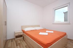a bedroom with a bed with orange sheets and a window at Apartmani Ruža in Novalja