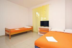 a room with two beds and a television in it at Apartmani Ruža in Novalja