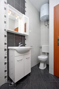 a bathroom with a white sink and a toilet at Apartmani Ruža in Novalja +37 photos