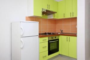 a kitchen with green cabinets and a white refrigerator at Apartmani Ruža in Novalja