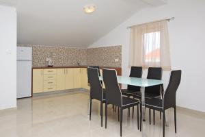 a kitchen with a table and black chairs at Apartmani Ruža in Novalja