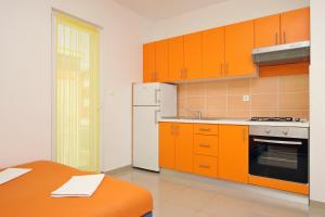 a kitchen with orange cabinets and a white refrigerator at Apartmani Ruža in Novalja