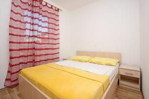 a bedroom with a bed with yellow sheets and a curtain at Apartmani Ruža in Novalja