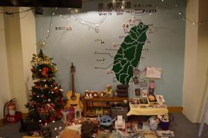 uma sala de Natal com uma árvore de Natal e um sinal na parede em Trip GG Hostel em Kaohsiung
