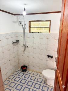 a bathroom with a toilet and a tile floor at Baruk Homestay in Katiet