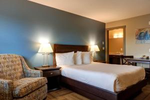 a hotel room with a bed and a chair at Vedder River Inn in Chilliwack