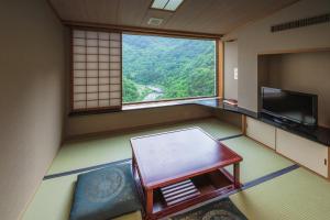 a room with a window and a bench and a television at Marumine Kanko Hotel in Aizuwakamatsu