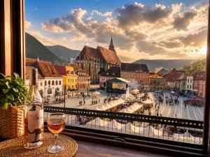 a glass of wine sitting on a table next to a window at Central View Piata Sfatului 7- Panoramic Apartment in Braşov